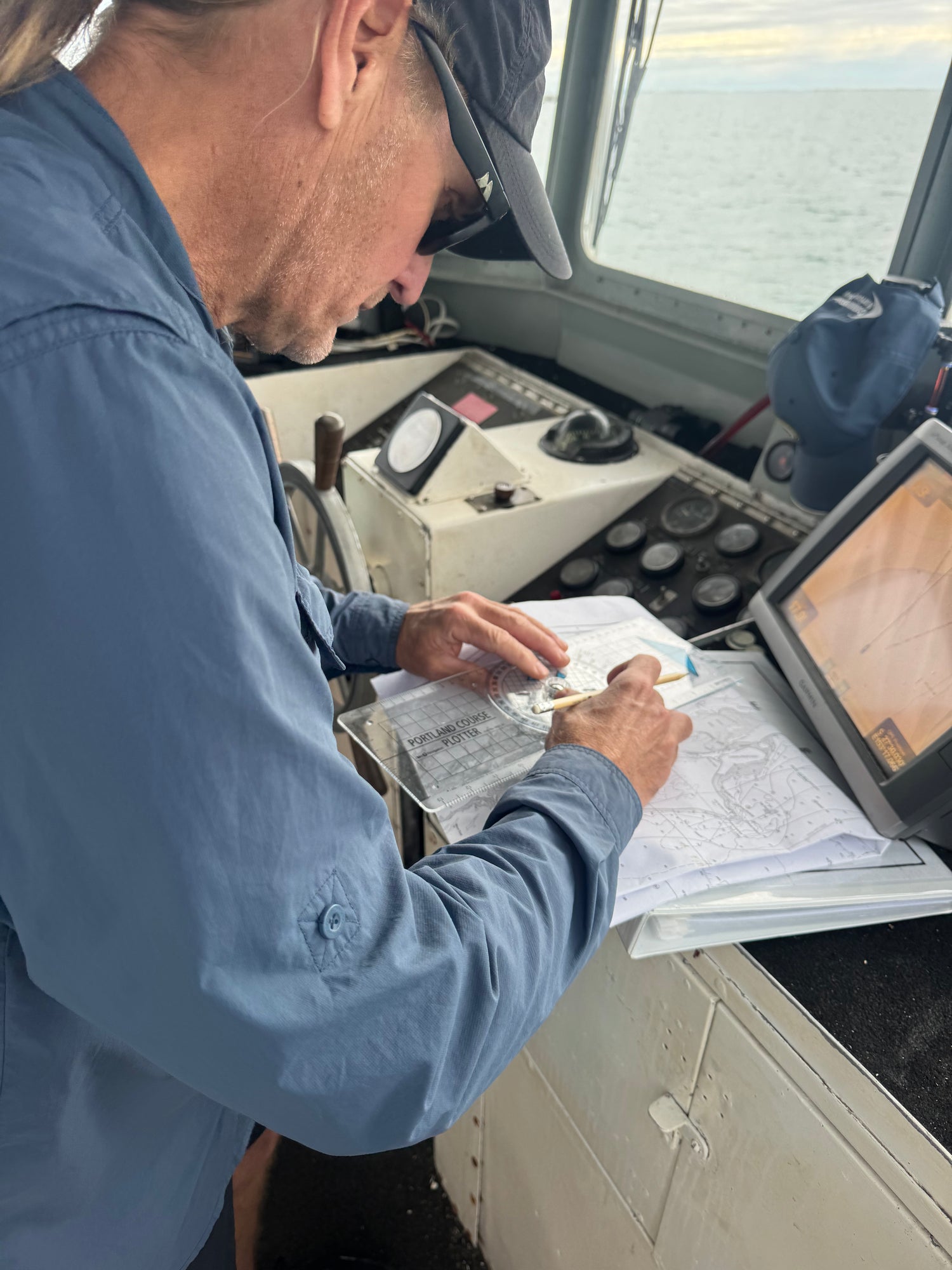 Coxswain Grade 1 student plotting a passage on a chart at the helm of a commercial vessel